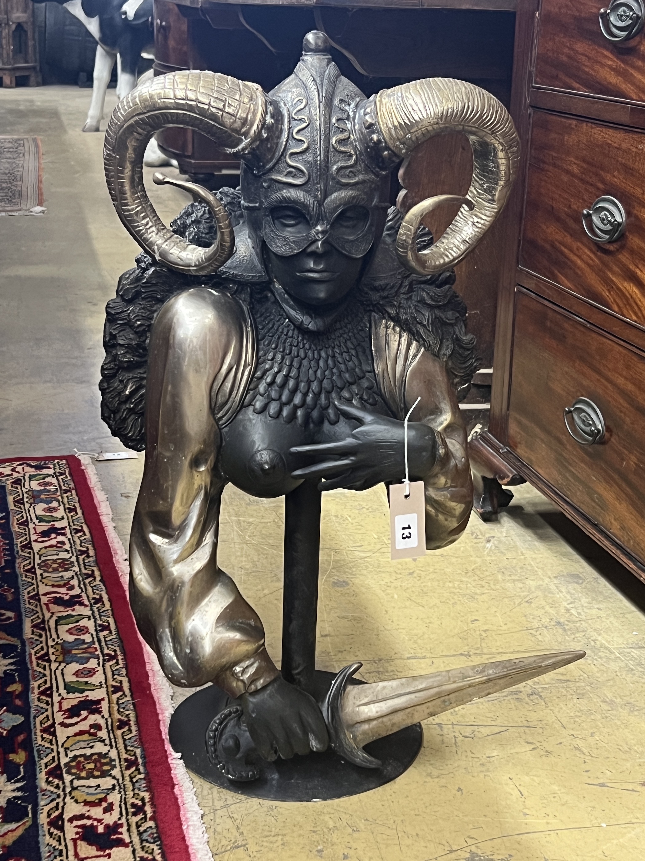 A patinated and polished metal masked female warrior bust on stand, height 70cm